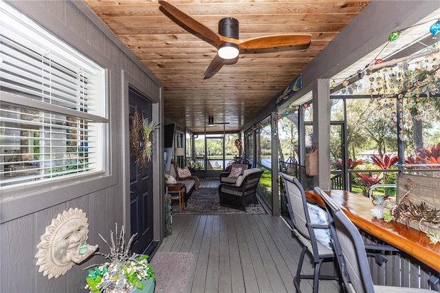 unfurnished sunroom with wood ceiling and a ceiling fan