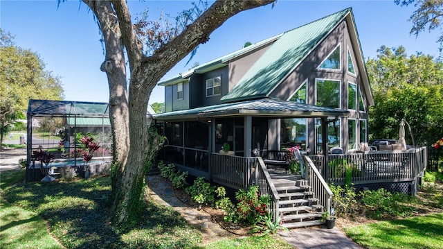 back of house featuring metal roof, a wooden deck, and stairs