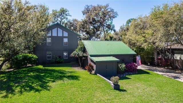 rear view of property featuring an outdoor structure, a yard, and metal roof