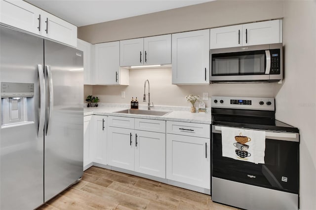 kitchen featuring white cabinetry, light wood-type flooring, appliances with stainless steel finishes, and a sink