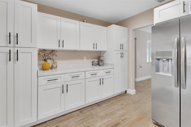 kitchen featuring white cabinets, stainless steel fridge with ice dispenser, baseboards, and light wood finished floors