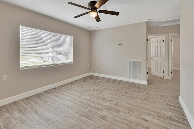 empty room featuring light wood finished floors, visible vents, a ceiling fan, and baseboards