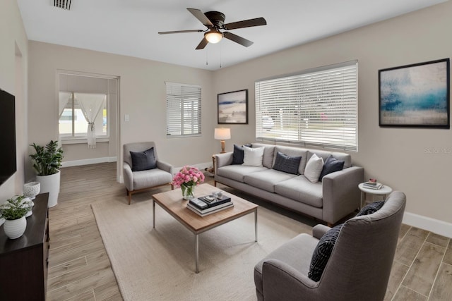 living area with visible vents, baseboards, light wood-type flooring, and ceiling fan