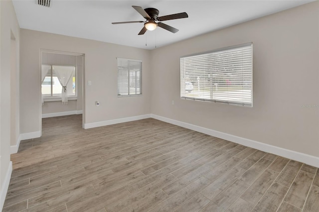 unfurnished room with light wood finished floors, a healthy amount of sunlight, baseboards, and ceiling fan