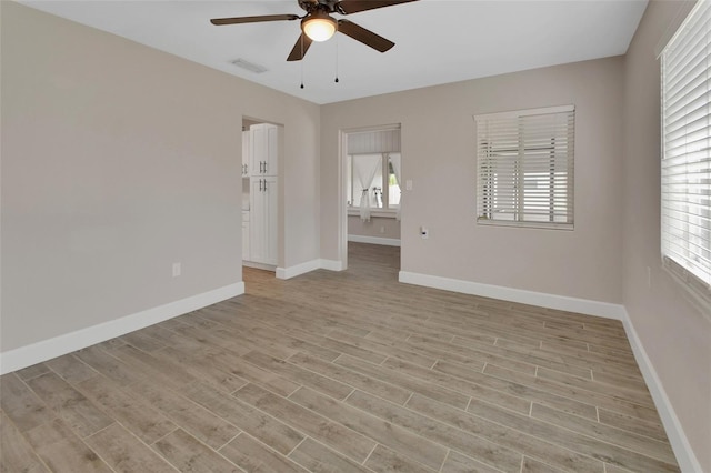 spare room with light wood-style flooring, baseboards, visible vents, and ceiling fan