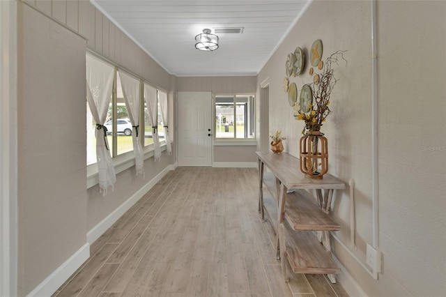 corridor featuring baseboards, light wood-type flooring, and ornamental molding