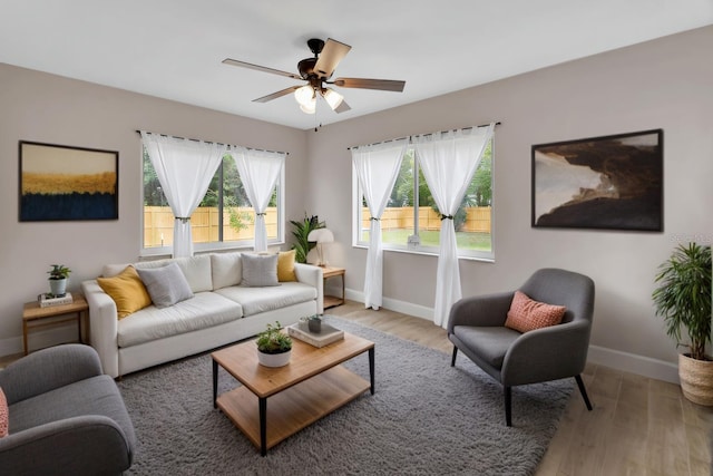 living area with light wood finished floors, ceiling fan, and baseboards