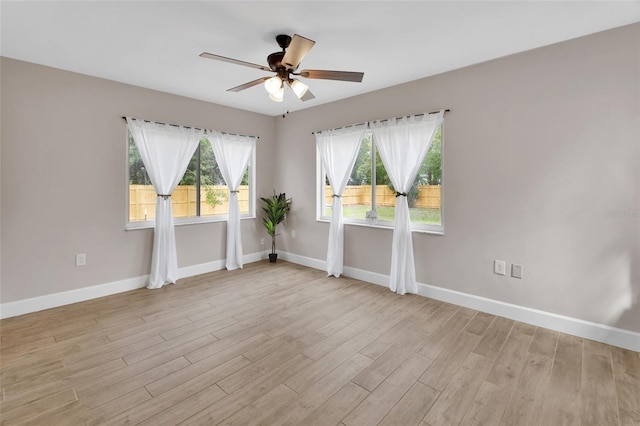 empty room with light wood-style flooring, a ceiling fan, and baseboards