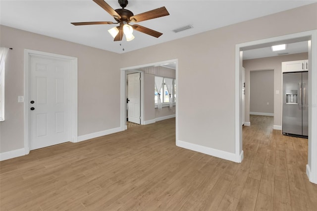 unfurnished room featuring ceiling fan, light wood-style floors, visible vents, and baseboards