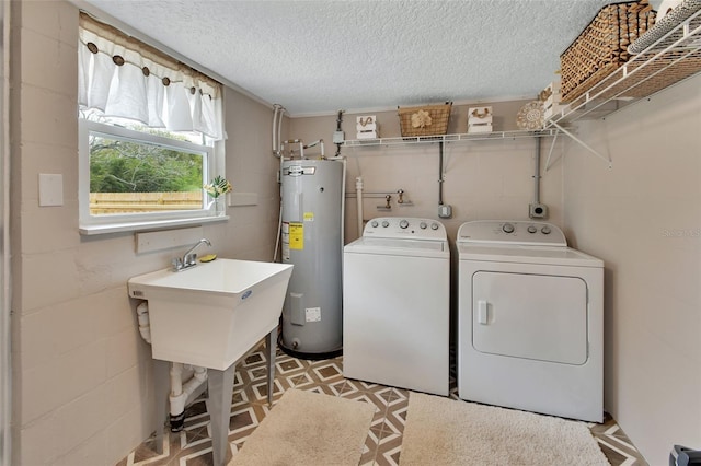 laundry room featuring washer and clothes dryer, water heater, concrete block wall, light floors, and laundry area