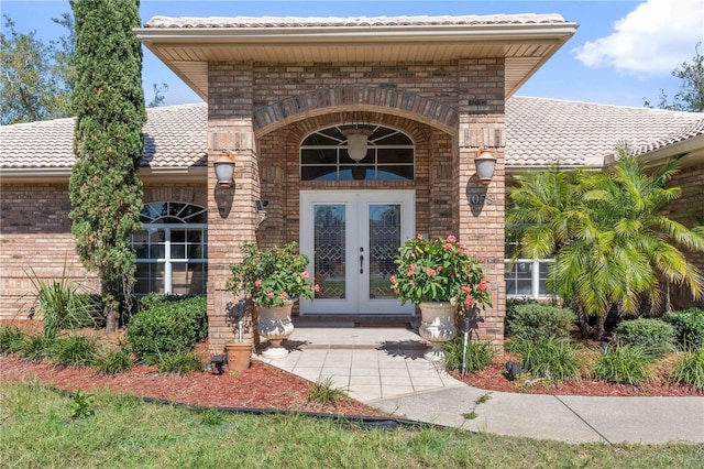 property entrance featuring french doors, brick siding, and a tiled roof