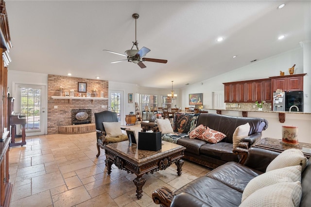 living area with a brick fireplace, stone tile floors, a ceiling fan, and a healthy amount of sunlight