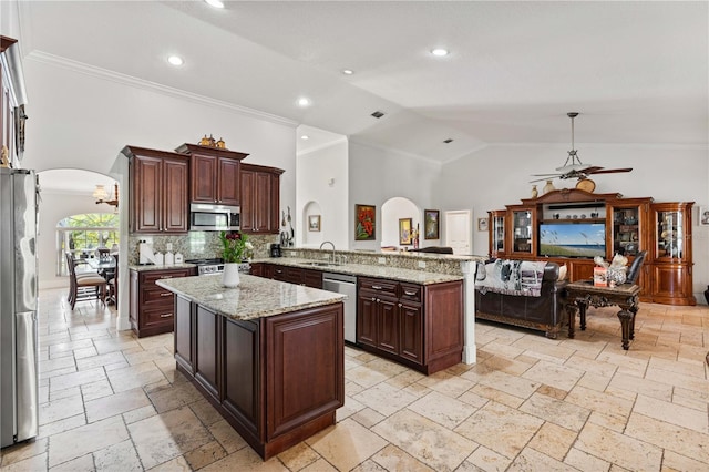kitchen featuring arched walkways, stone tile floors, appliances with stainless steel finishes, and a sink