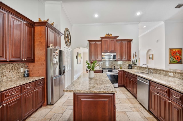 kitchen with a sink, stainless steel appliances, arched walkways, and stone tile floors
