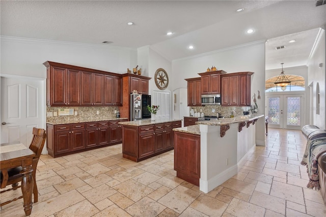 kitchen featuring stone tile floors, high vaulted ceiling, a peninsula, ornamental molding, and stainless steel appliances