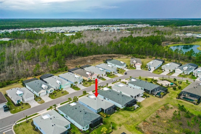 drone / aerial view with a forest view, a residential view, and a water view