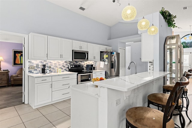 kitchen with stainless steel appliances, visible vents, a peninsula, and white cabinets