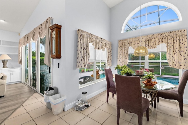 dining space with tile patterned floors, baseboards, and high vaulted ceiling