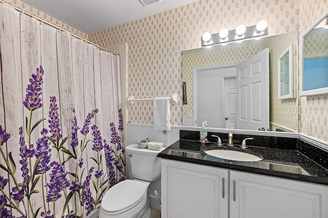 full bath featuring a wainscoted wall, visible vents, toilet, wallpapered walls, and vanity