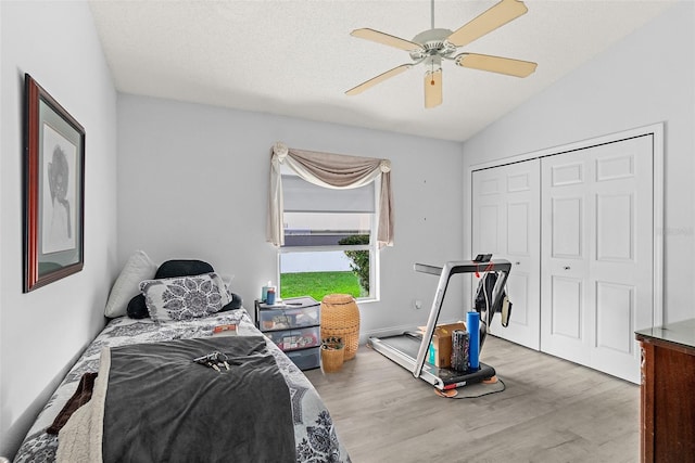 bedroom with a ceiling fan, wood finished floors, vaulted ceiling, a closet, and a textured ceiling