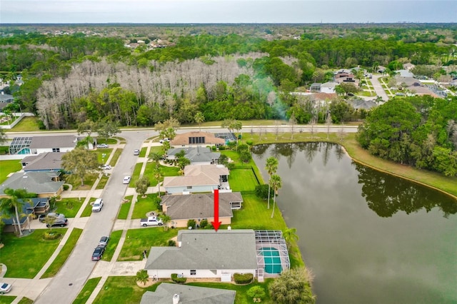 drone / aerial view featuring a forest view, a water view, and a residential view