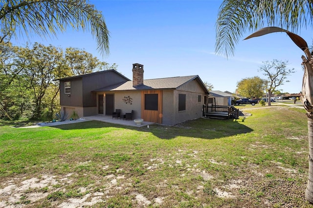 rear view of house with a yard, a patio area, and a chimney