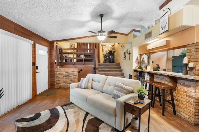 living area featuring ceiling fan, a textured ceiling, lofted ceiling, and wood finished floors