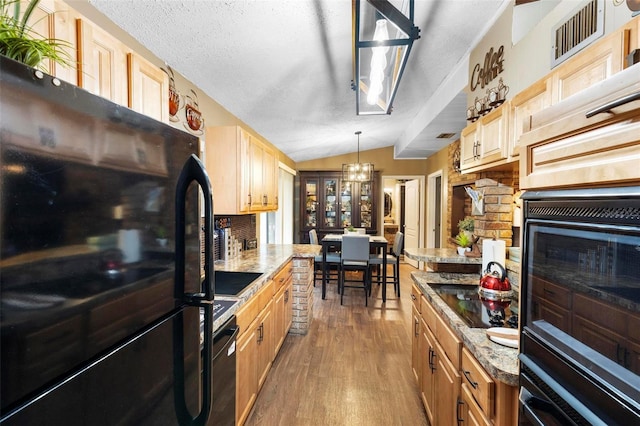 kitchen with black appliances, light brown cabinetry, lofted ceiling, wood finished floors, and a textured ceiling