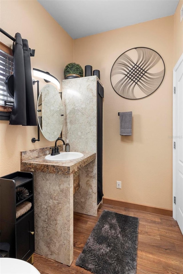 bathroom with visible vents, wood finished floors, baseboards, and a sink