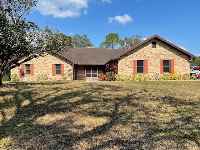 ranch-style house featuring a front lawn, brick siding, a sunroom, and a shingled roof