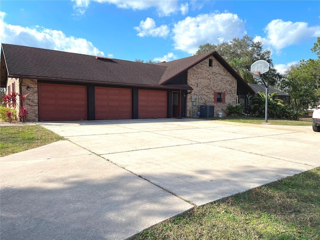 view of front facade featuring brick siding, a shingled roof, central AC unit, a garage, and driveway