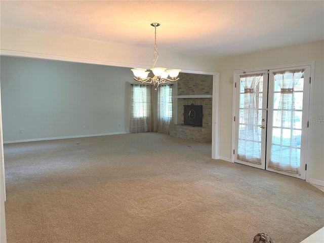 unfurnished living room with a chandelier, carpet flooring, a fireplace, and baseboards