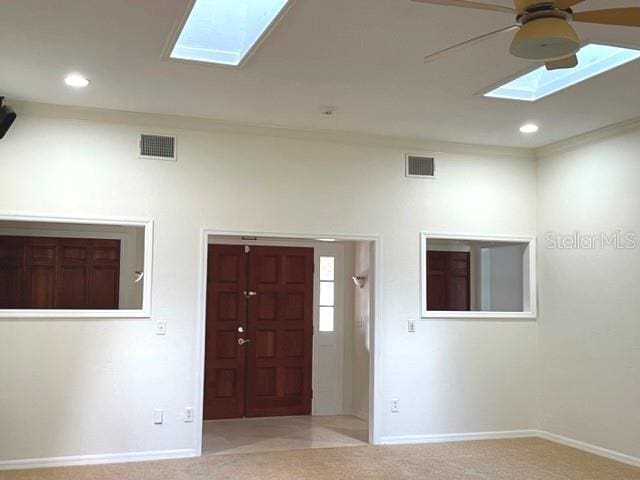 carpeted spare room featuring a ceiling fan, visible vents, baseboards, a skylight, and recessed lighting