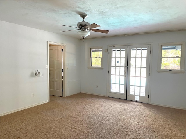 carpeted empty room featuring french doors, a textured ceiling, baseboards, and a ceiling fan