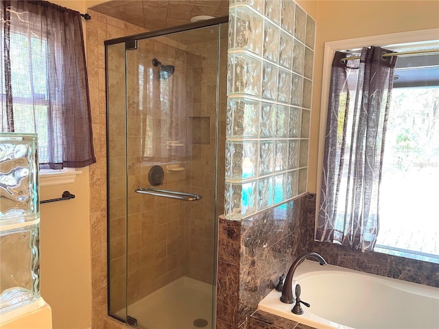 full bathroom with a wealth of natural light, a stall shower, and a garden tub