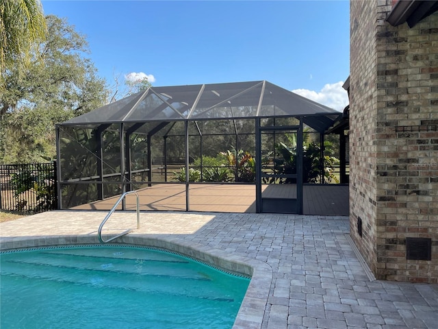 outdoor pool featuring glass enclosure, a patio, and fence