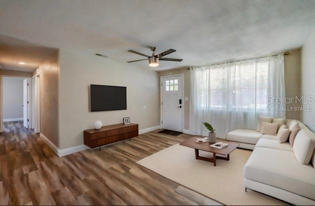 living room featuring a wealth of natural light, visible vents, baseboards, and wood finished floors