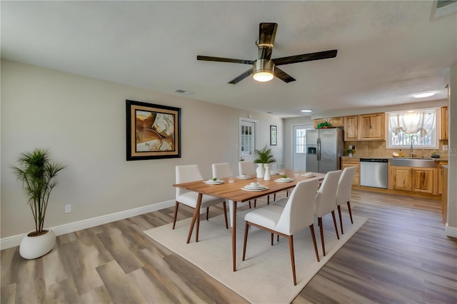 dining room featuring a ceiling fan, light wood-style flooring, baseboards, and visible vents