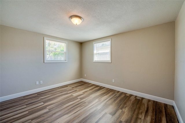 spare room featuring a textured ceiling, baseboards, and wood finished floors