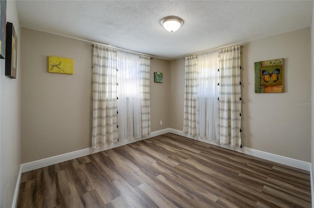 empty room with baseboards, a textured ceiling, and wood finished floors