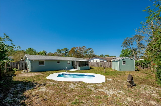 back of property with an outbuilding, a shed, a fenced backyard, and a sunroom