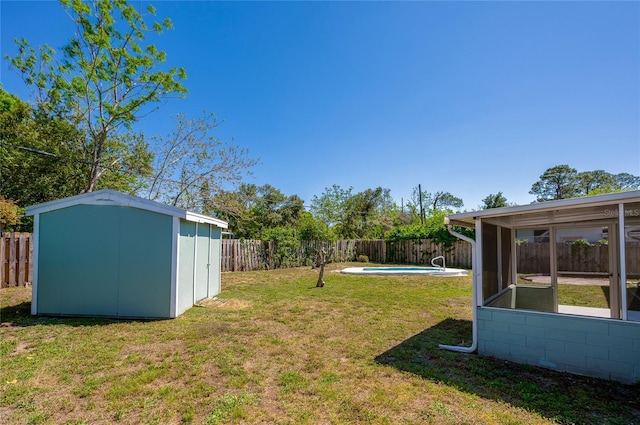 view of yard with an outdoor structure, a storage unit, a fenced backyard, and a sunroom