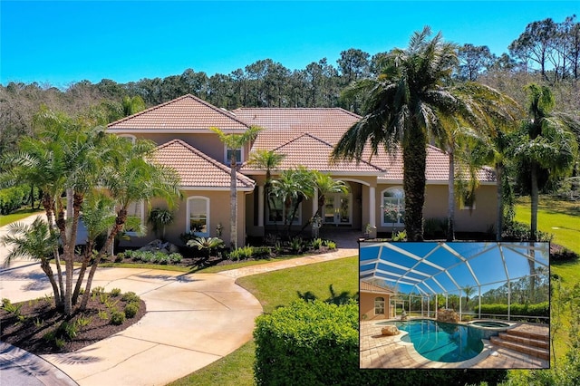 mediterranean / spanish house with a tile roof, a front lawn, a pool with connected hot tub, and stucco siding