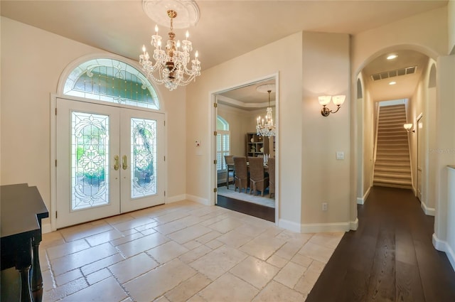 entrance foyer with visible vents, stairway, french doors, baseboards, and a chandelier