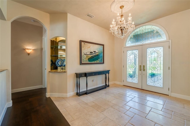 entryway featuring visible vents, baseboards, a chandelier, french doors, and stone tile flooring