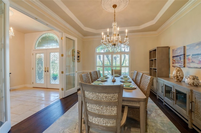 dining room with a tray ceiling, crown molding, a notable chandelier, and french doors