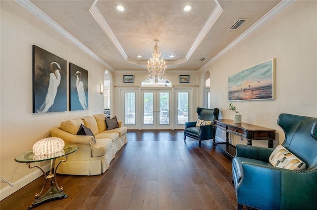 living room featuring a tray ceiling, dark wood-style floors, visible vents, and arched walkways