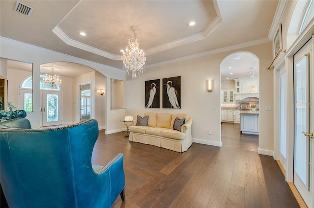 living room featuring a tray ceiling, arched walkways, an inviting chandelier, and visible vents