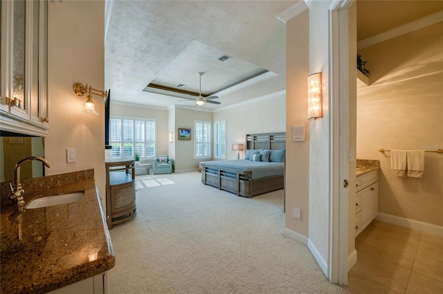 bedroom with visible vents, light carpet, a sink, crown molding, and a raised ceiling