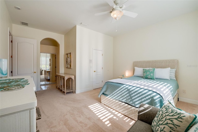 bedroom featuring visible vents, light carpet, arched walkways, baseboards, and ceiling fan